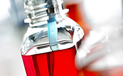 Laboratory technician performing sterile filtration of red cell culture media in a flask during media preparation.