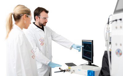 Two scientists in lab coats and gloves working with laboratory equipment. One is pointing at a computer screen displaying graphs, while the other looks on attentively. The scene takes place in a modern laboratory environment. Two scientists in lab coats and gloves working with laboratory equipment. One is pointing at a computer screen displaying graphs, while the other looks on attentively. The scene takes place in a modern laboratory environment.