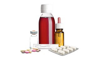 An assortment of medical items, including a bottle of red liquid medicine with a white cap, a small glass vial with a metal cap, a dropper bottle with amber-colored liquid, and various pills and capsules, some loose and some in blister packs.
