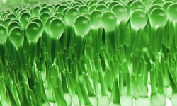 Illustration of lipids forming membrane around living cell with hydrophobic tails projecting inward and their polar head groups projecting outwards. Image shows a close-up of numerous green spoon heads arranged in tight, orderly rows, creating a patterned effect.