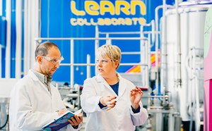 Two scientists in the MLab with bioreactors in the background.