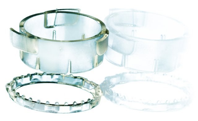 CellCrown™ 3D cell culture scaffold inserts Four transparent and semi-transparent plastic rings of varying sizes and designs, some with metal pins or teeth-like structures, laid out against a white background. These appear to be components possibly used in mechanical or laboratory settings.