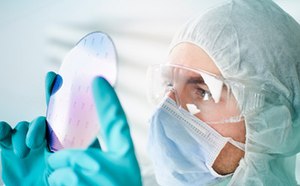 Scientist wearing protective clothing inspecting prefabricated pre-patterned electronic device substrate