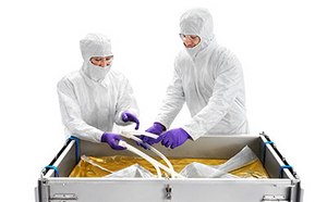Two technicians in a sterile environment are operating a Mobius 2D and 3D single-use assembly system. They are dressed in full protective cleanroom suits, complete with hoods and masks, ensuring a contamination-free process.