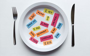 The image features an indistinctly blurred plate of food with a fork on the left and a knife on the right, all against a stark white background.