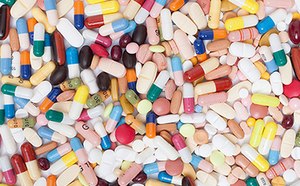A diverse collection of pharmaceutical pills and capsules. They come in various shapes and colors, including pink, yellow, white, blue, and red. Some capsules are clear or opaque with different colored ends.