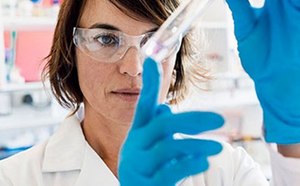A scientist or lab technician in a white coat and blue gloves is engaged in an experiment or analysis in a laboratory setting.