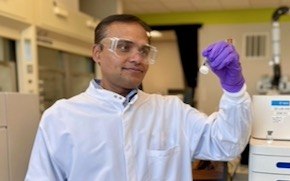 Karwa가 실험실에서 mRNA 순도 측정을 도와주는 분석 기기 옆에 서 있습니다.