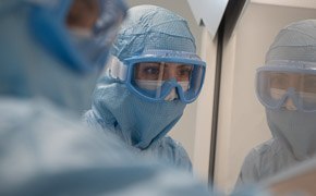 Pre-Clinical Offering Two operators, close up in personal protective equipment at a laminar flow cabinet preparing reagents