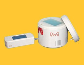 LightOX PhotoReact 365 against a yellow background. The off-white cylindrical base unit features a vibrant M logo and is shown with its removable locking lid. On the left side, a control unit is attached to the base unit through a USB cable.