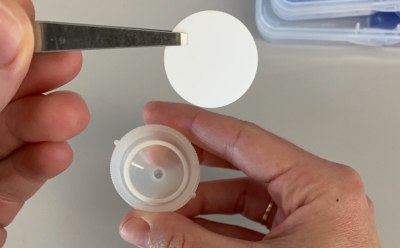 Swinnex<sup>®</sup> Filter Handling Photograph of a person’s hands using forceps to manipulate a cut disc filter.